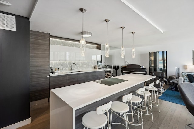 kitchen featuring dark brown cabinetry, modern cabinets, a kitchen island, hanging light fixtures, and light countertops