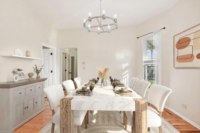 dining space featuring light wood-style floors, baseboards, and a notable chandelier