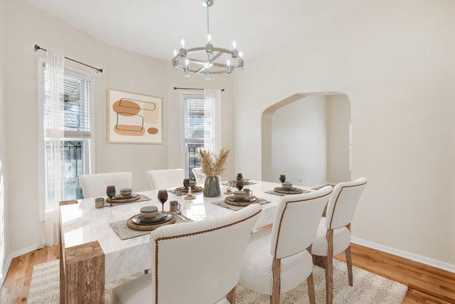 dining room featuring a notable chandelier, arched walkways, light wood-style flooring, and baseboards