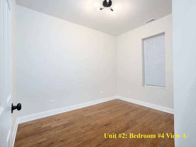 spare room featuring wood finished floors, visible vents, and baseboards