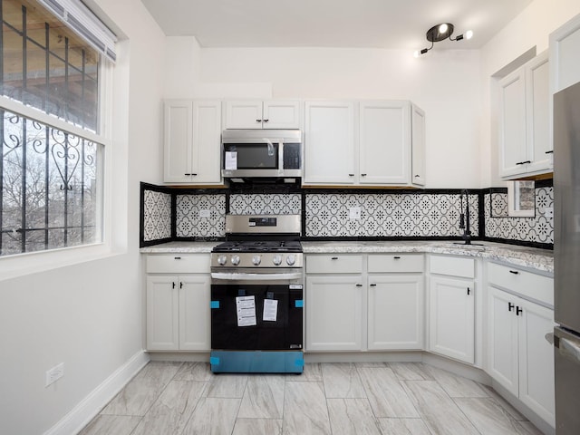 kitchen featuring appliances with stainless steel finishes, white cabinets, and tasteful backsplash