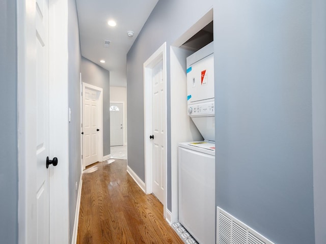 hallway with recessed lighting, wood finished floors, visible vents, baseboards, and stacked washing maching and dryer