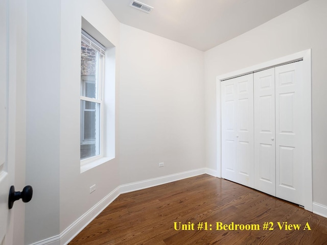 unfurnished bedroom with a closet, visible vents, dark wood finished floors, and baseboards