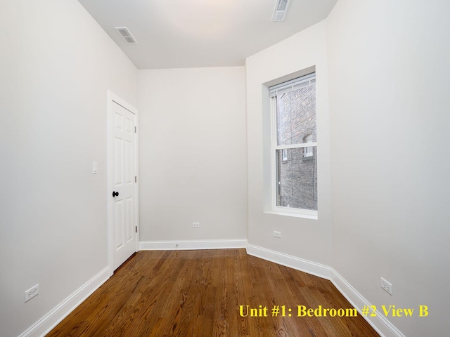 unfurnished room featuring baseboards, visible vents, and wood finished floors