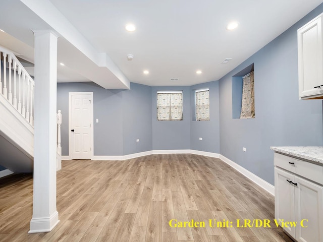 basement featuring light wood-style flooring, stairs, and baseboards