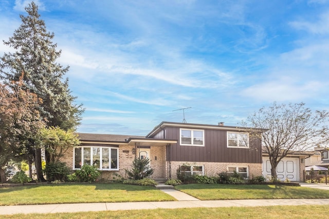 split level home featuring a garage, brick siding, and a front yard