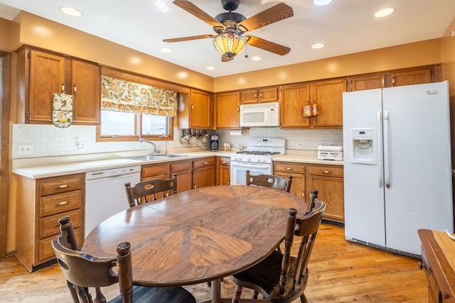 kitchen featuring brown cabinetry, white appliances, light countertops, and a sink
