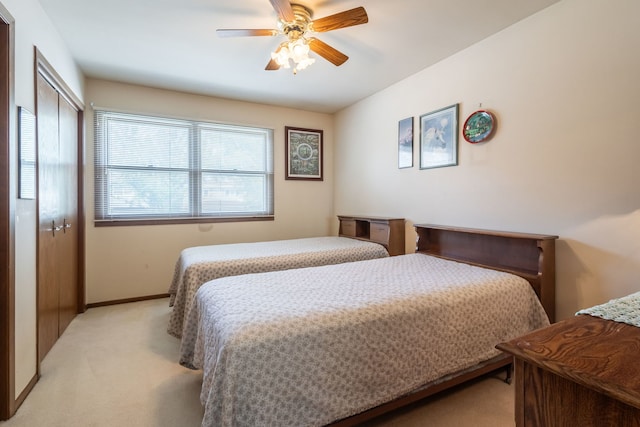 bedroom with a closet, light carpet, ceiling fan, and baseboards