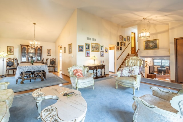 living room featuring high vaulted ceiling, visible vents, stairway, and an inviting chandelier