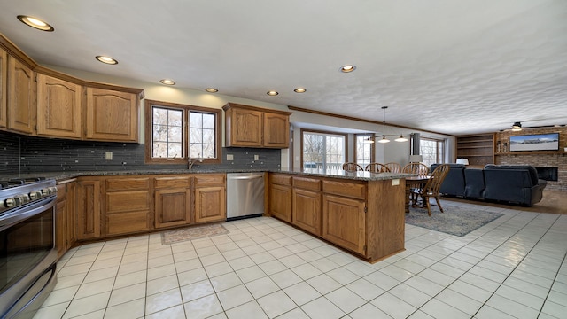 kitchen featuring brown cabinetry, open floor plan, a peninsula, stainless steel appliances, and pendant lighting