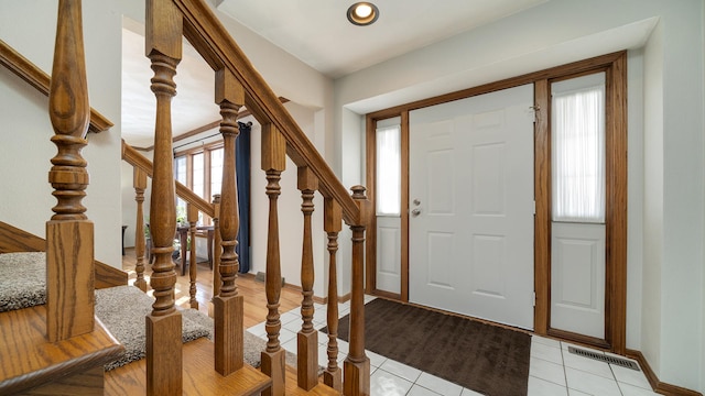 entryway with light tile patterned flooring, visible vents, baseboards, and stairs