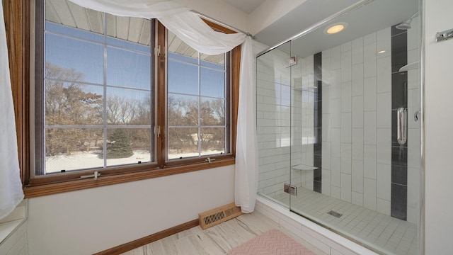 bathroom featuring a wealth of natural light, a shower stall, visible vents, and baseboards