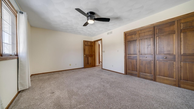 unfurnished bedroom featuring a ceiling fan, visible vents, light carpet, and baseboards