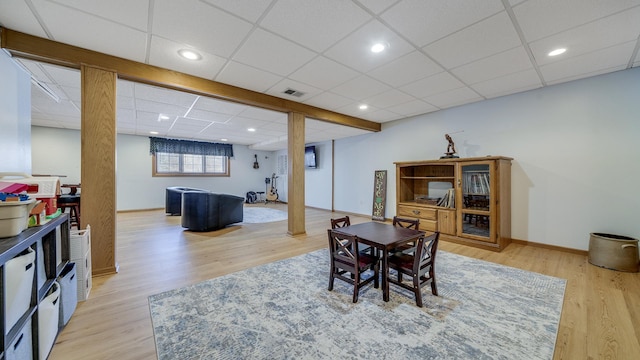 dining area with light wood-style floors, visible vents, a drop ceiling, and baseboards