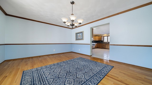 unfurnished room featuring light wood-type flooring, an inviting chandelier, and crown molding