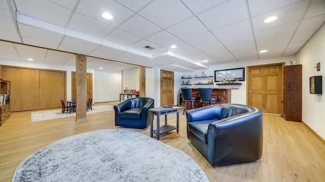 living room featuring visible vents, a paneled ceiling, a bar, light wood-style floors, and recessed lighting