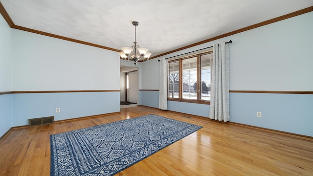 empty room featuring visible vents, crown molding, an inviting chandelier, and wood finished floors