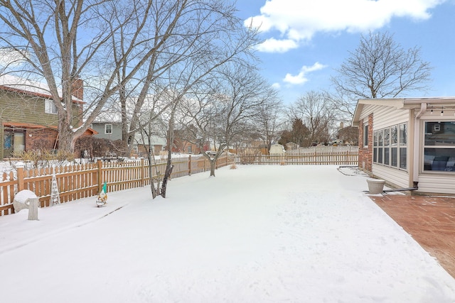 yard covered in snow with a fenced backyard and a residential view