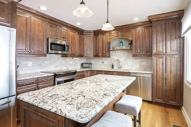 kitchen featuring a sink, stainless steel appliances, backsplash, and light wood-style flooring