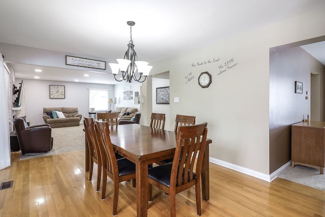 dining space featuring light wood-type flooring, baseboards, visible vents, and a chandelier