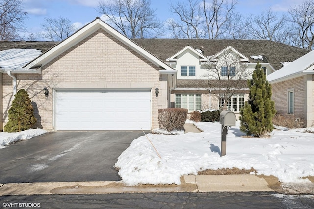 view of front of house with an attached garage, aphalt driveway, and brick siding