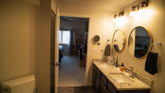 bathroom with double vanity, a sink, and toilet