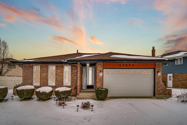 view of front of property featuring brick siding, fence, and an attached garage