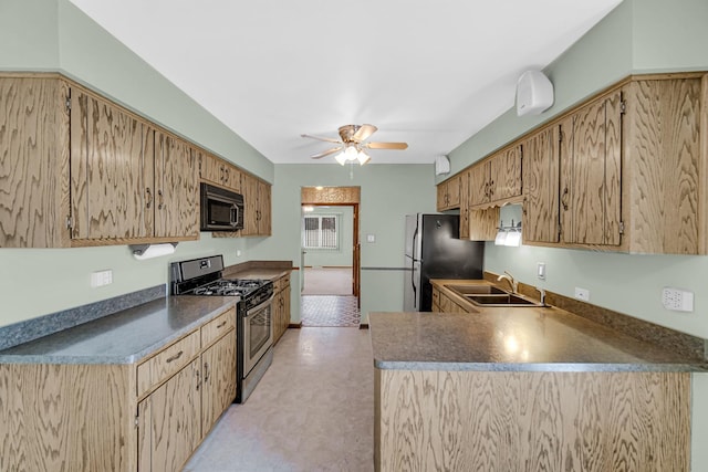 kitchen with dark countertops, ceiling fan, freestanding refrigerator, a sink, and gas stove