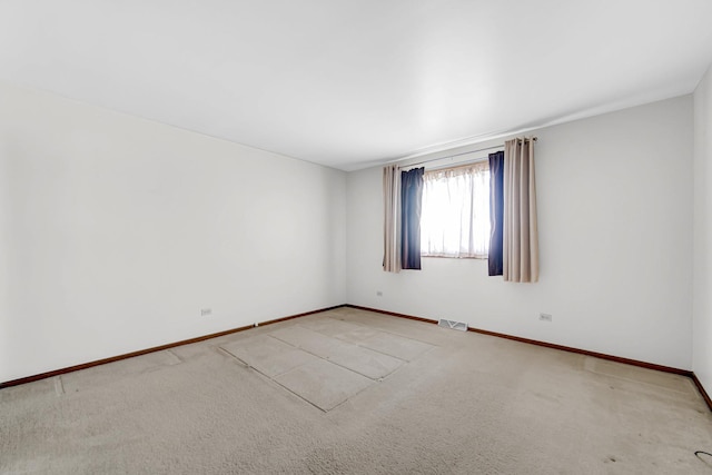 unfurnished room with baseboards, visible vents, and light colored carpet