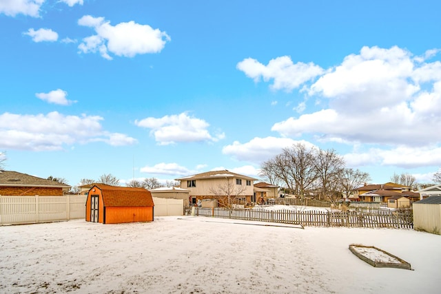 yard covered in snow featuring a shed, a residential view, fence, and an outbuilding