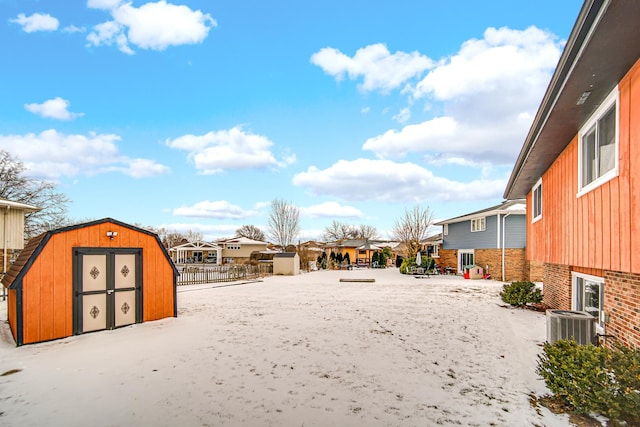 view of yard with an outbuilding, a storage shed, central AC unit, fence, and a residential view