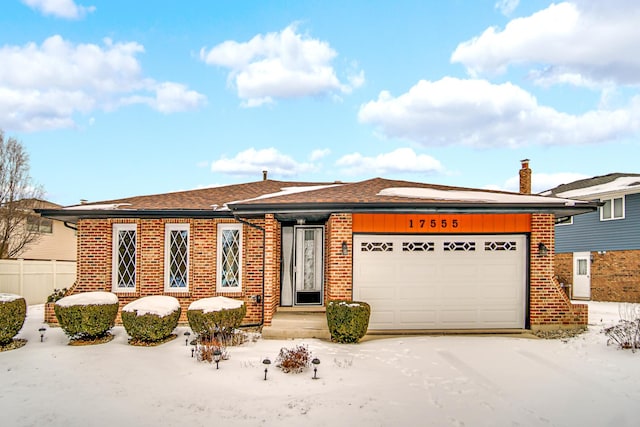 view of front of house with a garage, brick siding, and fence