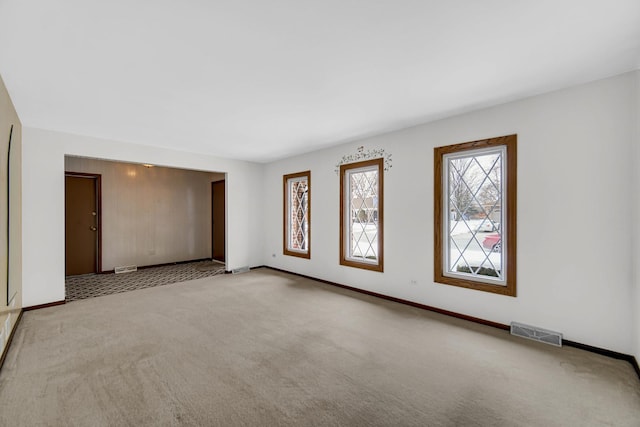 spare room featuring light carpet, visible vents, and baseboards