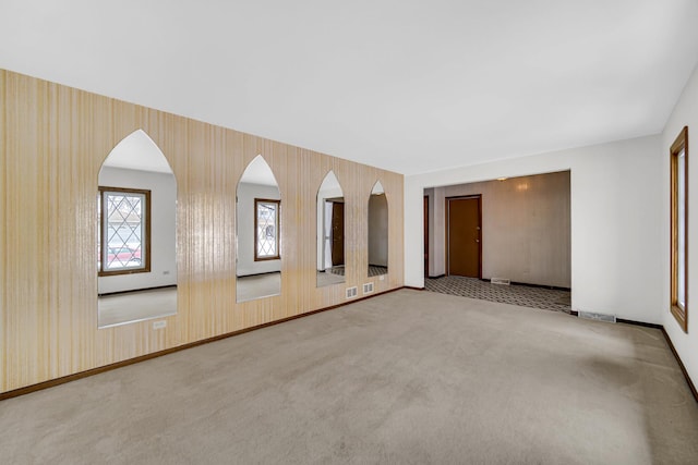 spare room featuring carpet floors, baseboards, and wallpapered walls