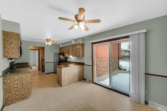 17555 Rosewood Ln, Tinley Park, IL 60487 - kitchen featuring appliances with stainless steel finishes, a peninsula, a ceiling fan, brown cabinets, and dark countertops