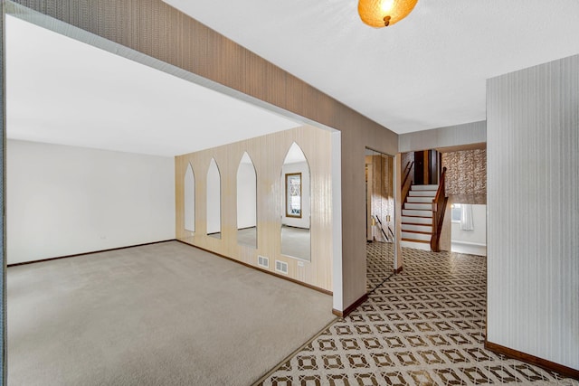 hall with carpet flooring, visible vents, baseboards, stairs, and wallpapered walls