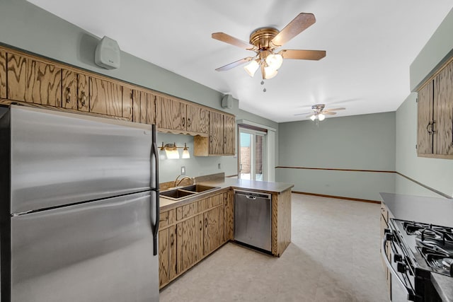 kitchen with stainless steel appliances, a peninsula, a sink, baseboards, and brown cabinets