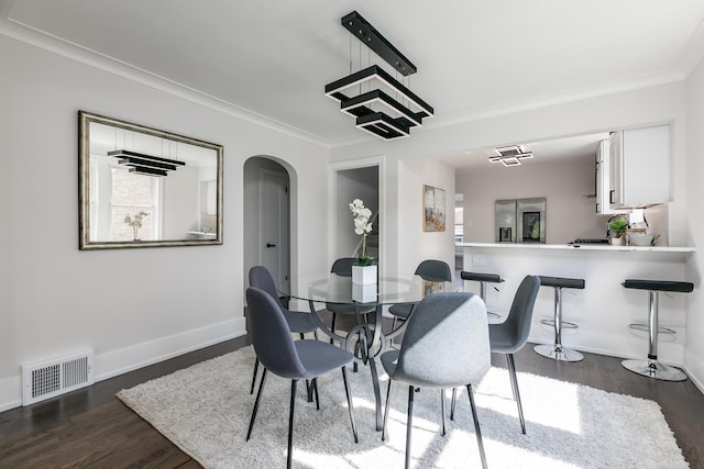 dining room with arched walkways, dark wood-style flooring, visible vents, and crown molding