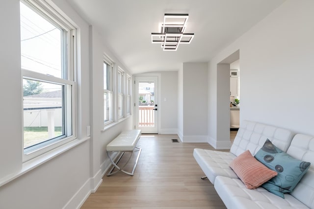 foyer with light wood-style flooring, visible vents, vaulted ceiling, and baseboards