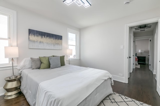 bedroom with multiple windows, baseboards, and dark wood-type flooring