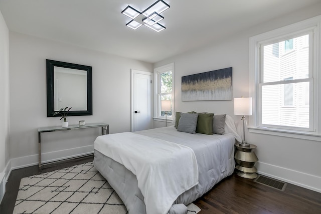 bedroom with baseboards, visible vents, and wood finished floors