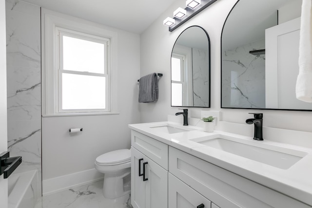 full bathroom with toilet, marble finish floor, double vanity, and a sink