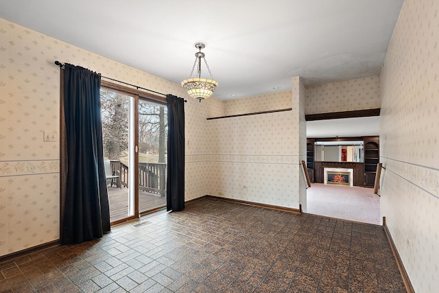 spare room featuring wallpapered walls, visible vents, baseboards, and a glass covered fireplace