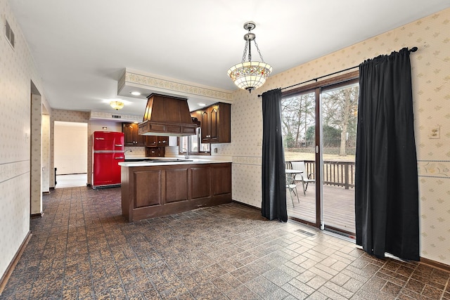 kitchen with custom range hood, light countertops, visible vents, and wallpapered walls