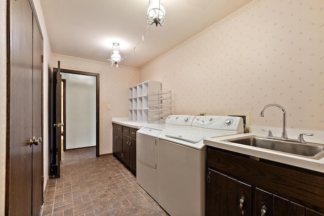 laundry room featuring washing machine and dryer, cabinet space, a sink, and wallpapered walls