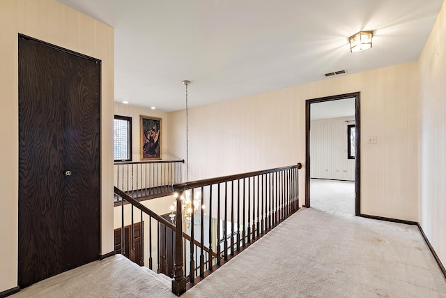 corridor with light carpet, visible vents, and an upstairs landing