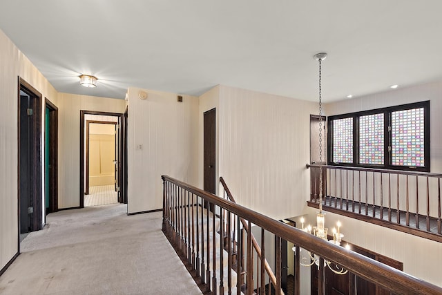 hall with light colored carpet and an upstairs landing