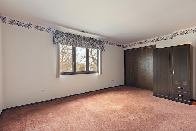 unfurnished bedroom featuring light carpet, a closet, and visible vents