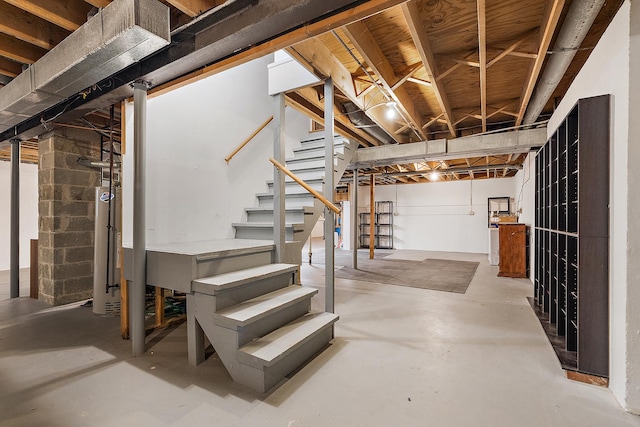 unfinished basement with concrete block wall, water heater, and stairs