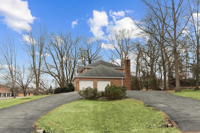 view of property exterior with brick siding, a yard, a chimney, a garage, and driveway